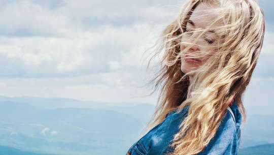 woman with eyes closed and the wind blowing through her hair